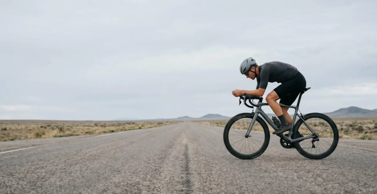 Cycliste en position aérodynamique mains en bas du cintre, vue d'ensemble minimaliste