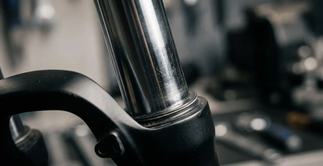 Gros plan macro sur les plongeurs chromés d'une fourche de VTT en compression